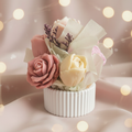 Pink and cream wax melt bouquet with roses and lavender in a white ribbed pot on a dusty rose background